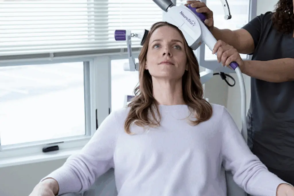 The image depicts a patient receiving TMS, a non-invasive brain stimulation technique that may help alleviate symptoms of depression.