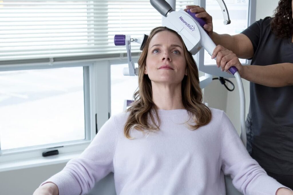 This image depicts a patient undergoing transcranial magnetic stimulation (TMS) therapy, highlighting the medical equipment involved.