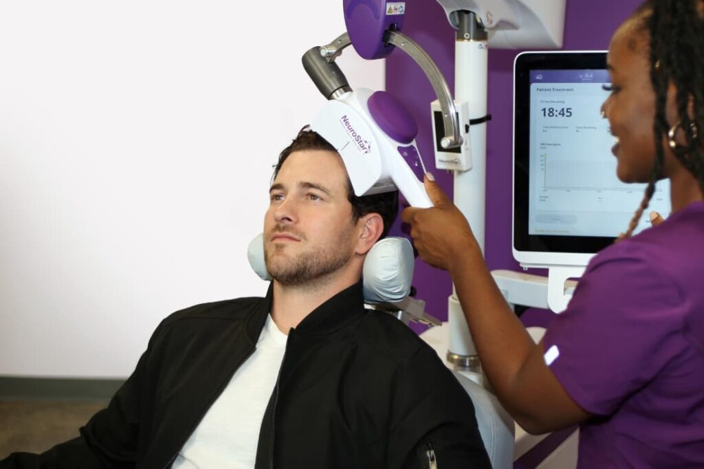 What Is Accelerated TMS demonstrated as a clinician operates a NeuroStar device on a male patient in a treatment clinic.