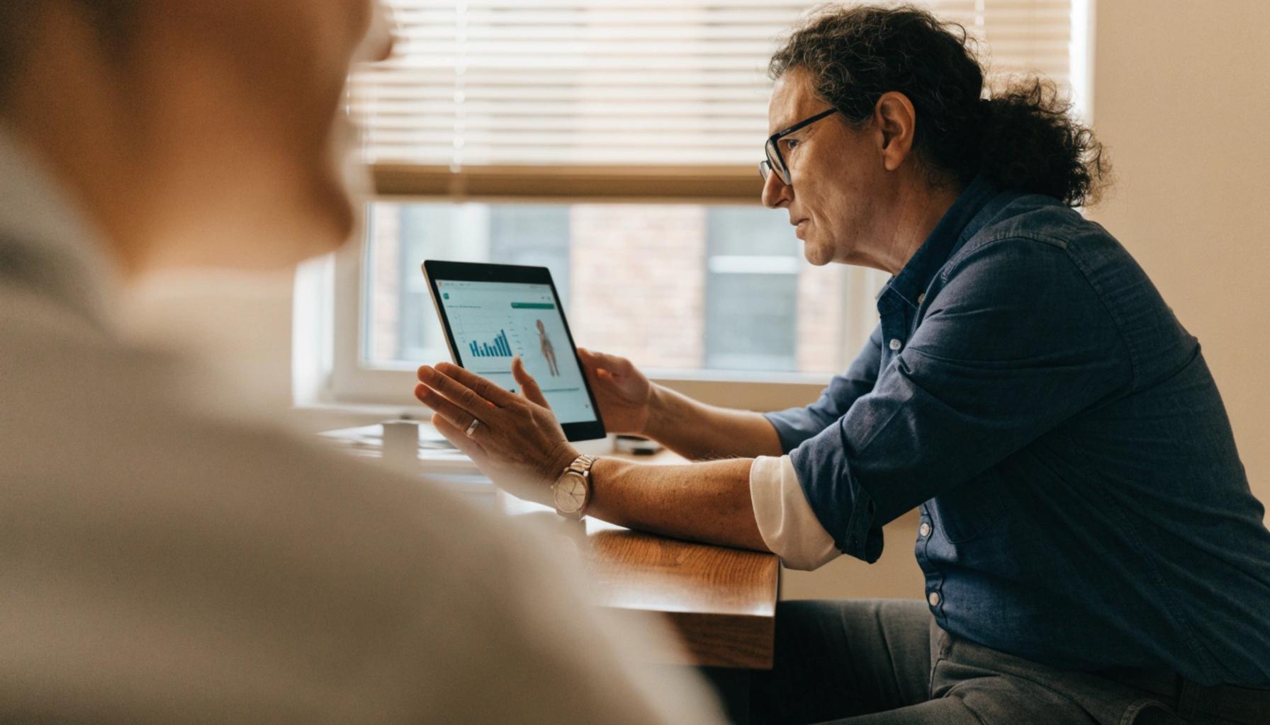 Clinician explaining accelerated TMS therapy options to a patient on a digital tablet during a psychiatric consultation.